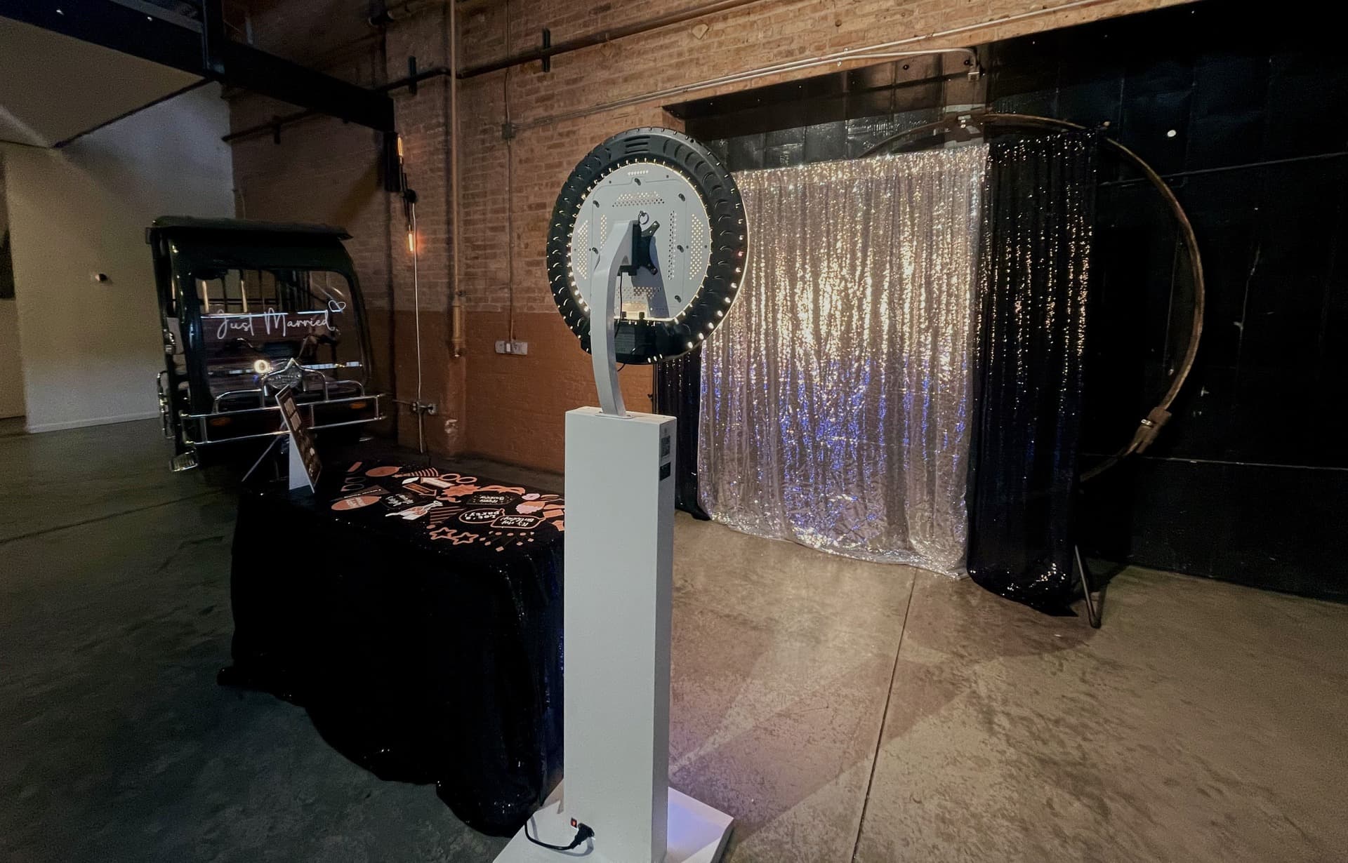 A real KandyBooth wedding setup with the circular booth, props table, and a silver and black sequin backdrop